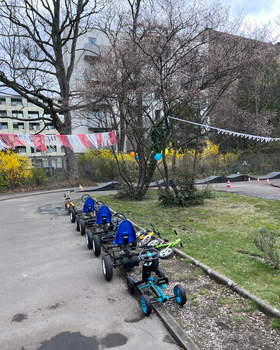 Ein Foto der Fahrbahn der Jugendverrkehrsschule in der Bremer Straße. Es sind Tretautos und -Räder zu sehen und Wimpel und Ballons, die zum Saisonstart aufgehängt wurden. 