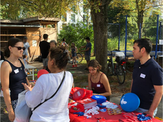 Foto des Stands der Linksfraktion Berlin Mitte beim Sommerfriedensfest. Im Bild sind Jonna Dickershoff, Samiullah Malekzadeh und Hannah Gerlof, die mit einer Besucherin des Festes spricht.