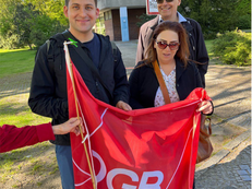 Gruppenfoto: Die Bezirksverordneten  Deniz Seyhun, Rüdiger Lötzer und Leonard Diederich halten eine Fahne des DGB Kreisverbands Mitte.