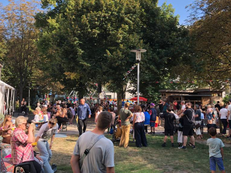 Foto vom Sommerfriedensfests. Dutzende Menschen sind im Sonnenschein auf die verschiedenen Attraktionen verteilt.